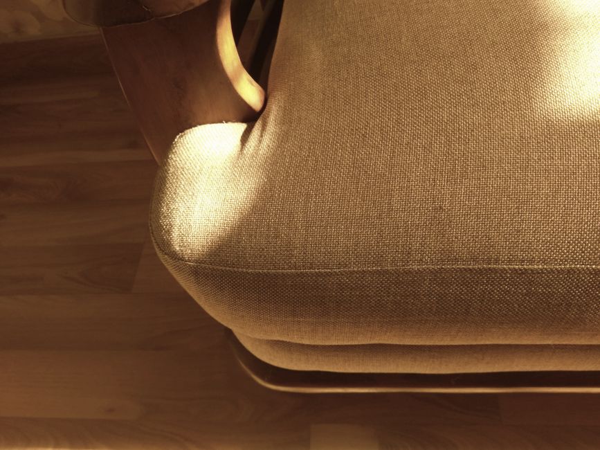 Brown fabric sofa catching warm sunlight, casting shadows indoors.